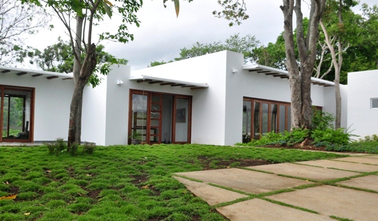Casa Balcones: casa de una planta con muros blancos y ventanales de madera